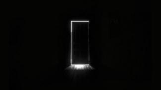 Zifiri karanlık bir alanın içerisinde kapalı bir kapının kenarlarından ışık sızıyor.