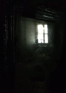 Karanlık bir evin içi, yalnızca içeriye sızan ışıkla pencere görüntüleniyor.