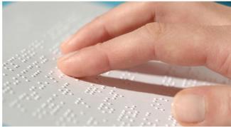 Braille ile yazılmış bir sayfa ve sayfadaki noktalar üzerinde gezinen çok yakın planda çekilmiş parmaklar
