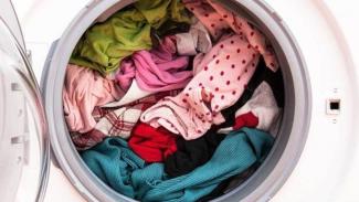 Kapağı açık bir çamaşır makinasının içindeki renkli çamaşırlar yakın plandan çekilmiş. Makine içi tamamen dolu.