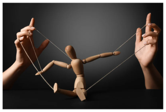 Görselde  gri bir fon önünde, parlak bir şekilde aydınlatılmış bir sahneyi gösteriliyor. Görüntünün merkezinde, parlak kahverengi bir tahta manken (kukla) bulunuyor. Manken oturur veya uzanır pozisyonda, dizleri bükülmüş ve kolları yana doğru açık vaziyette. Mankenin uzuvlarına bağlı ipler, sahnenin her iki yanından uzanan iki farklı insan eli tarafından tutuluyor. Bu eller, mankeni kontrol ediyormuş gibi görünüyor. 